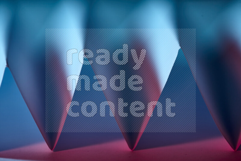 A close-up abstract image showing sharp geometric paper folds in blue and red gradients