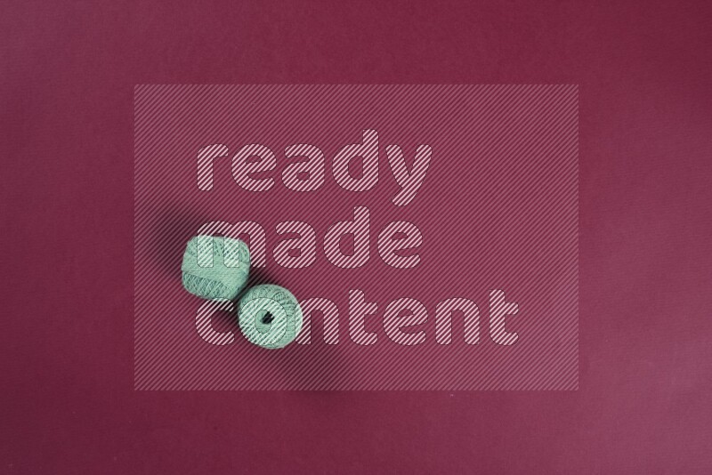 A green and red collection of sewing and tailoring tools arranged on a red background