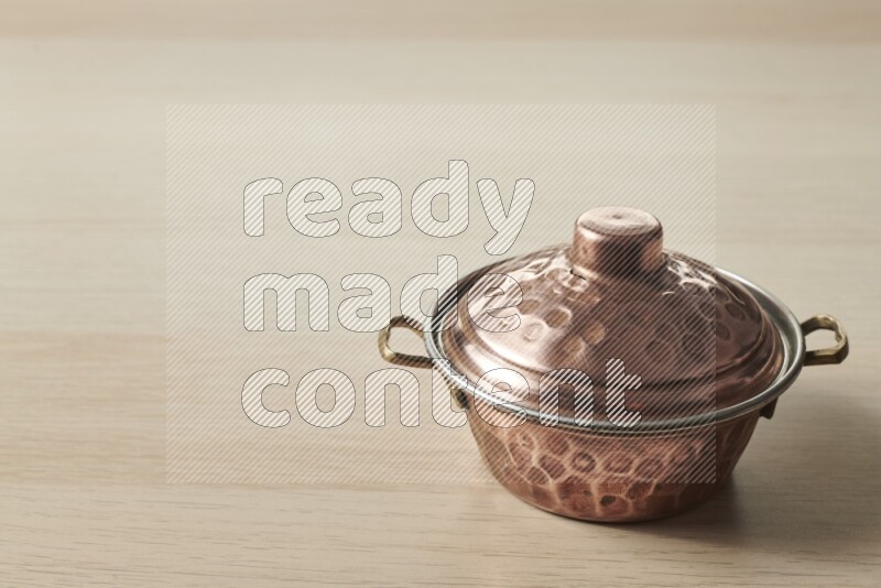 A small copper pot on light wooden background
