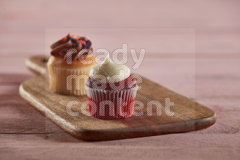 Red velvet mini cupcake topped with cream on a wooden board