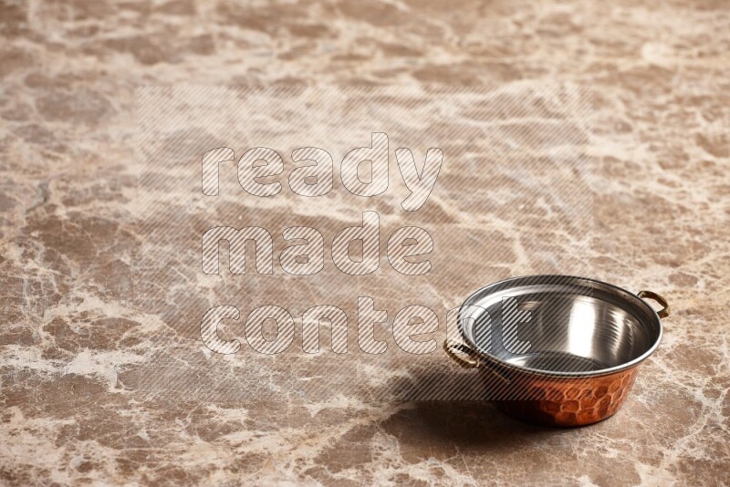 A small copper pot on beige marble background