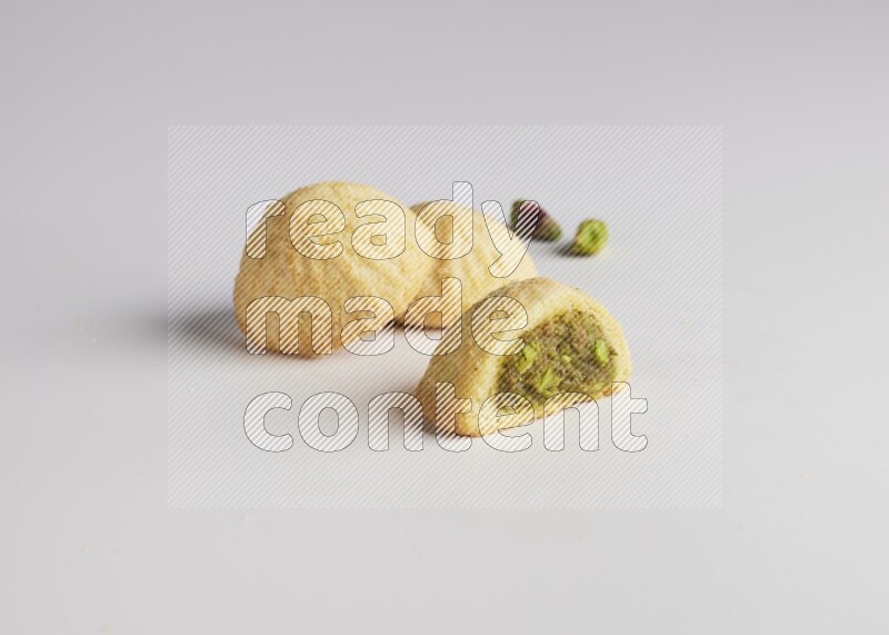 Three Pieces of Maamoul filled with pistachio paste  one of them is cut direct on white background