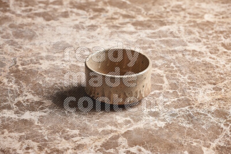 A beige pottery oven bowl on beige marble background