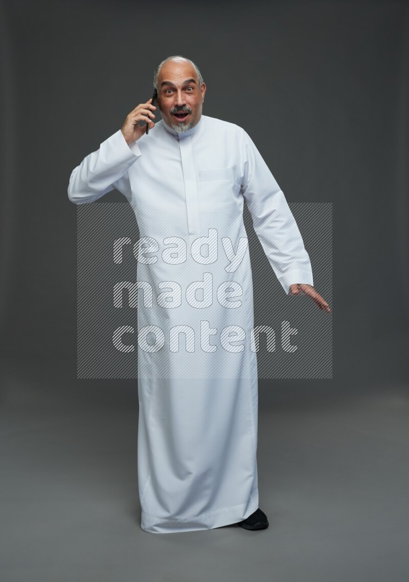 Saudi man without shomag Standing talking on phone on gray background