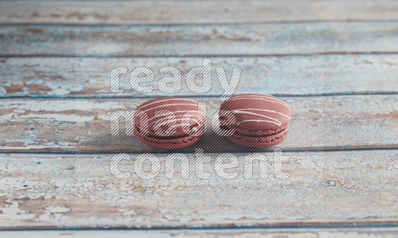 45º Shot of two Red Poppy Flower macarons on light blue wooden background
