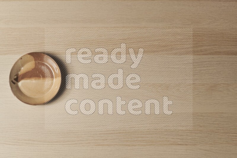 صحن فخاري متعدد الألوان على خلفية خشبية فاتحة