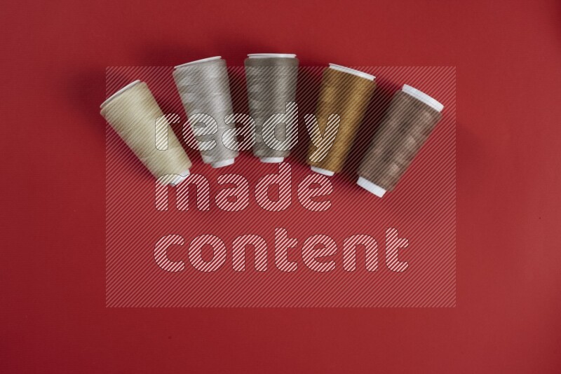 A brown and red collection of sewing and tailoring tools arranged on a red background