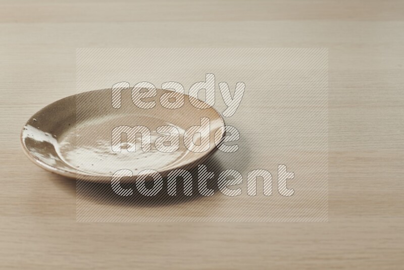 A beige pottery plate on light wooden background