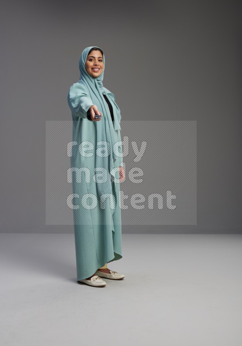 Saudi Woman wearing Abaya standing holding car key on Gray background