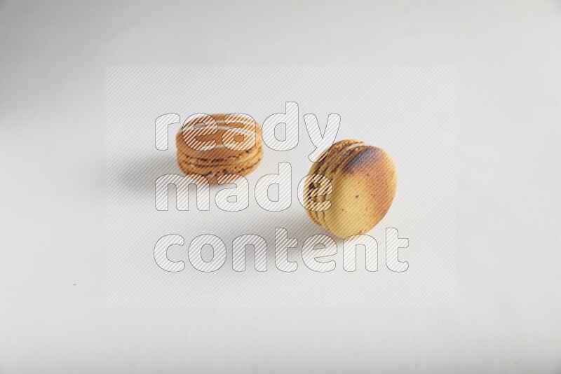 45º Shot of of two assorted Brown Irish Cream, and Yellow Crème Brulée macarons on white background