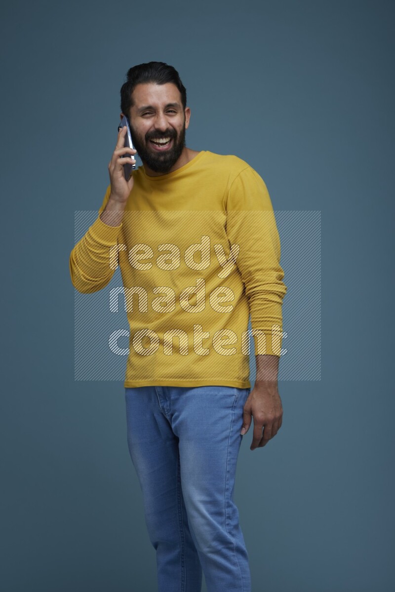 A man having a calling in a blue background wearing a yellow shirt