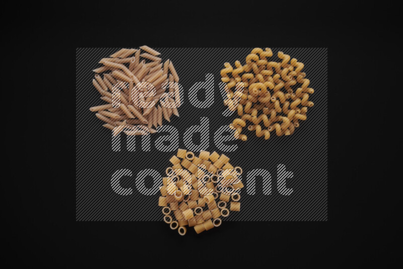 Different pasta types in bunches on black background
