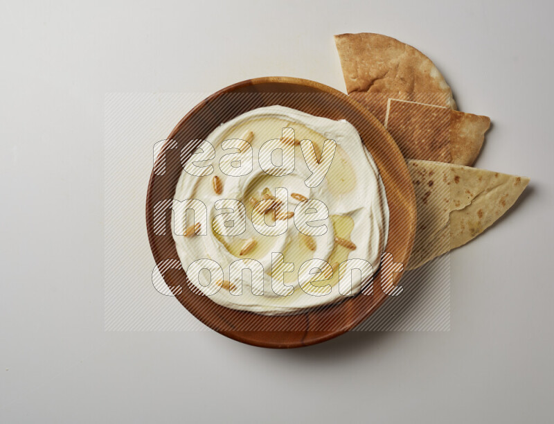 Lebnah garnished with pine nuts in a wooden plate on a white background