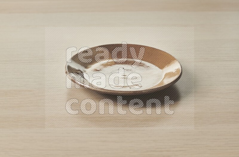 صحن فخاري متعدد الألوان على خلفية خشبية فاتحة