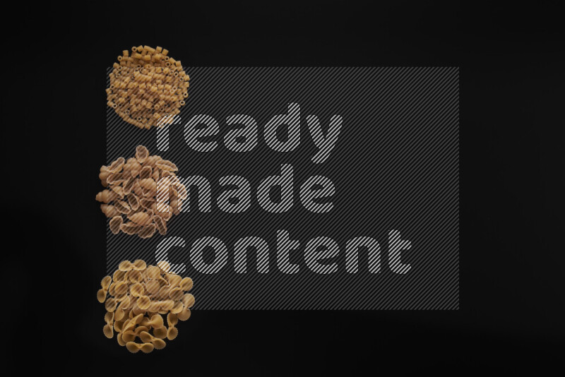 Different pasta types in 3 bunches on black background