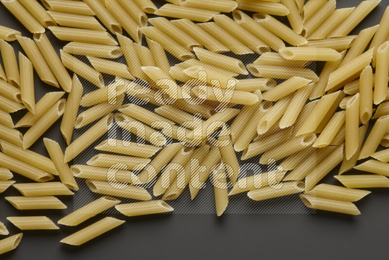 Mini penne pasta on grey background