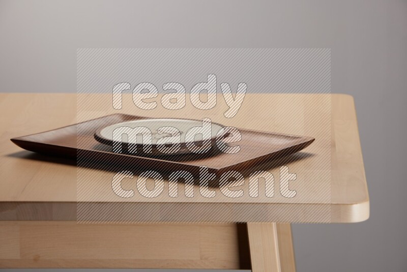 multicolored plate on a rectangular wooden tray on the edge of wooden table