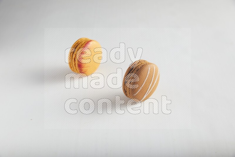 45º Shot of of two assorted Brown Irish Cream, and Orange Exotic macarons on white background