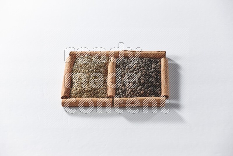 2 squares of cinnamon sticks full of black peppers and cumin on white flooring