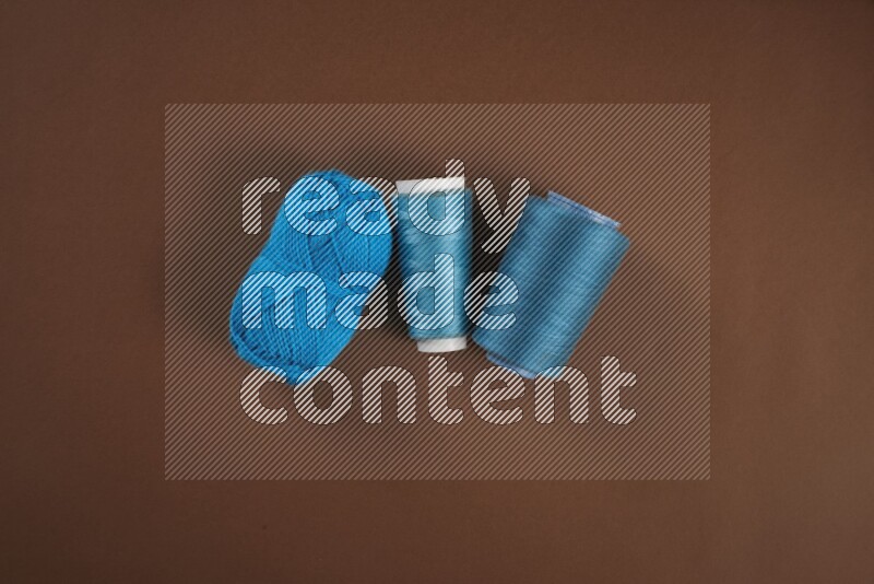 A blue collection of sewing and tailoring tools arranged on a brown background