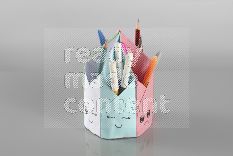 Origami pen holder on grey background