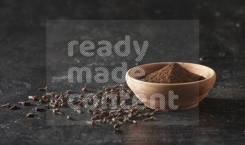 وعاء خشبي ممتلئ ببودرة القرنفل علي خلفية سوداء