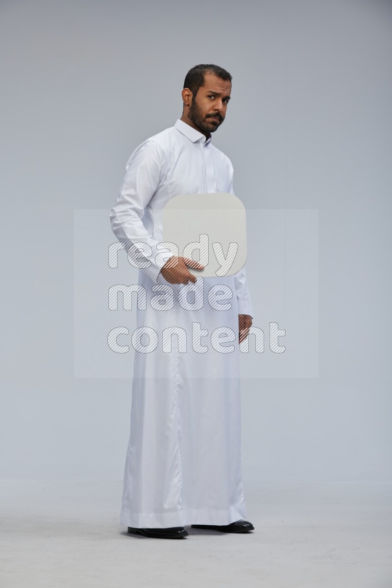 Saudi man wearing Thob standing holding social media sign on Gray background