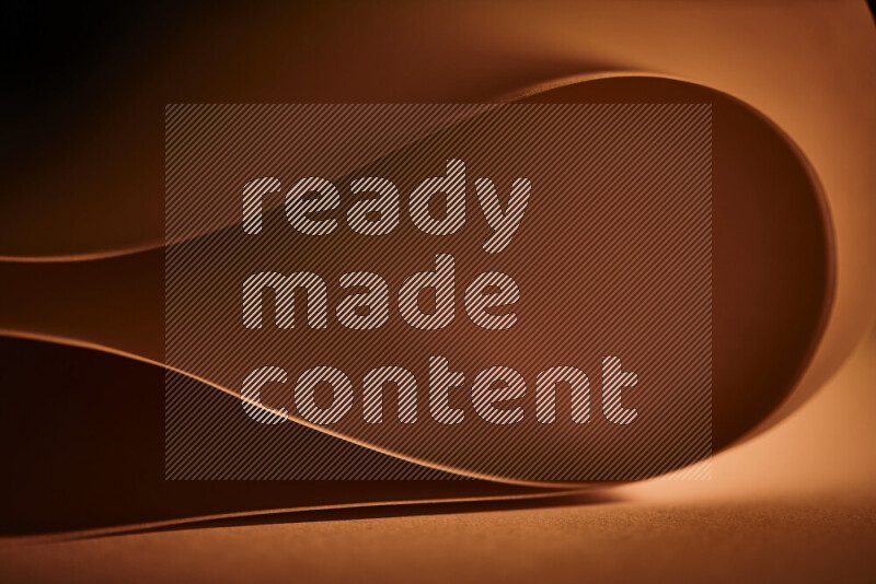 An abstract art piece displaying smooth curves in orange gradients created by colored light