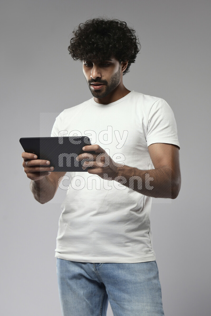 A man wearing casual standing and gaming on a tablet on white background