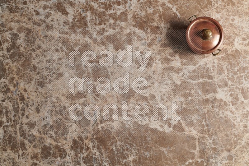 A small copper pot on beige marble background