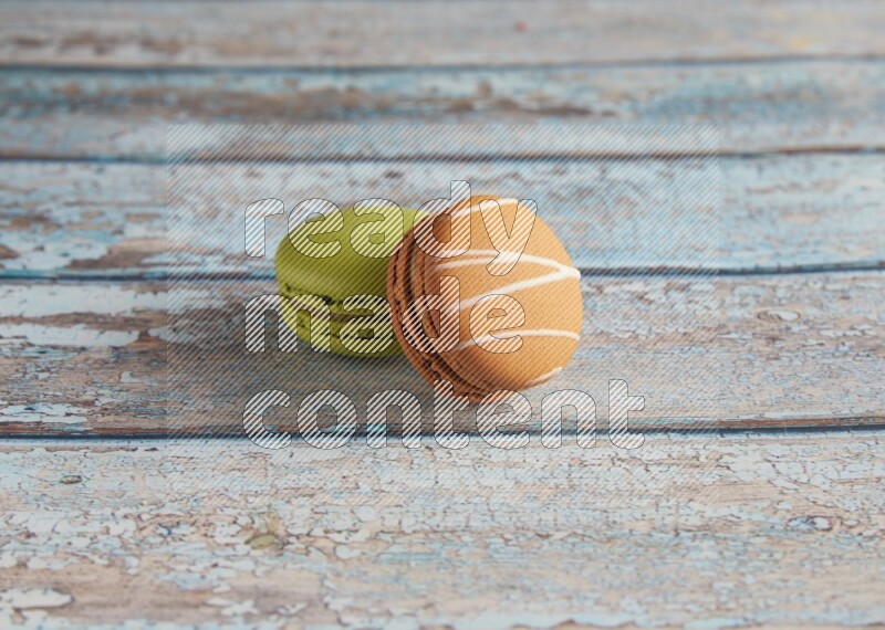 45º Shot of of two assorted Brown Irish Cream, and Green Pistachio macarons  on light blue background