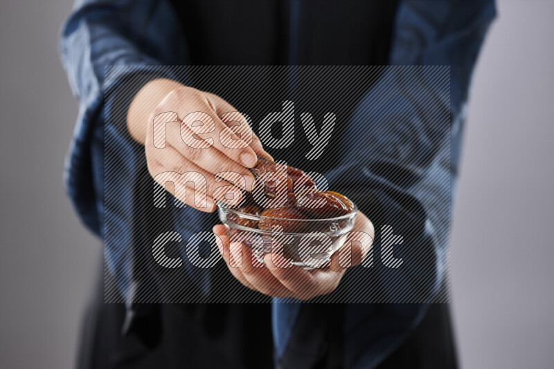 Woman in abaya holding dates in different positions