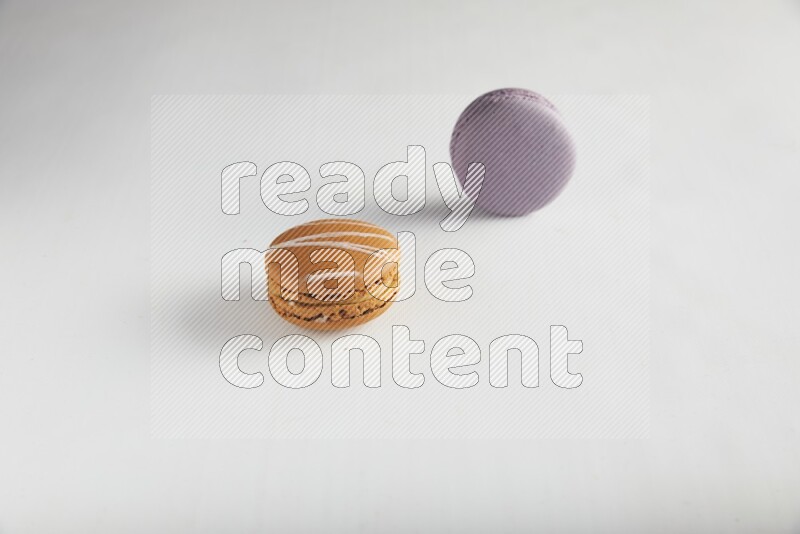 45º Shot of of two assorted Brown Irish Cream, and Purple Blueberry macarons on white background