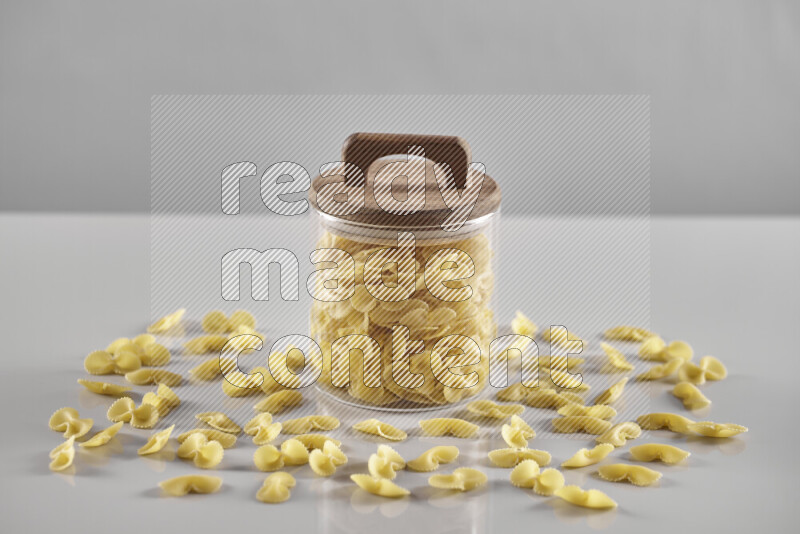 Raw pasta in a glass jar on light grey background