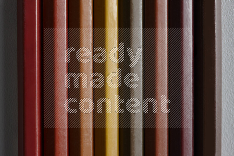 A collection of colored pencils arranged showcasing a gradient of brown hues on grey background