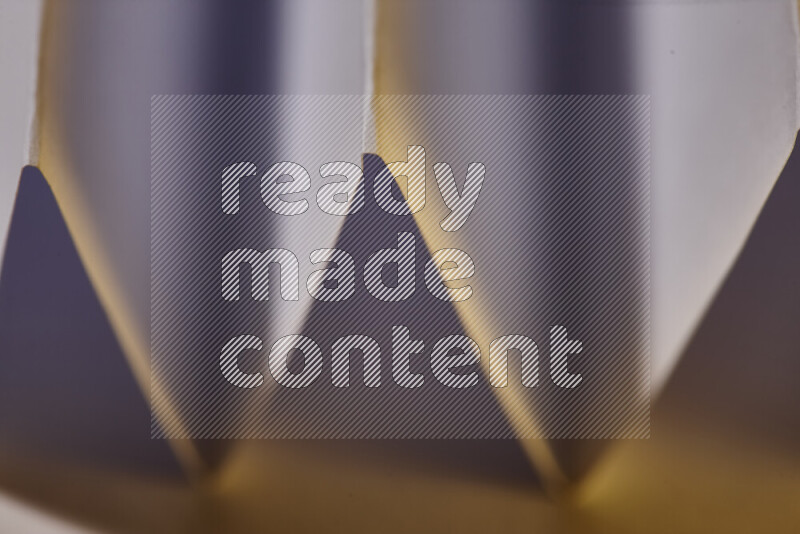 A close-up abstract image showing sharp geometric paper folds in white gradients and warm tones