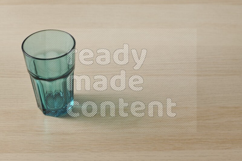 A turquoise glass cup on light wooden background