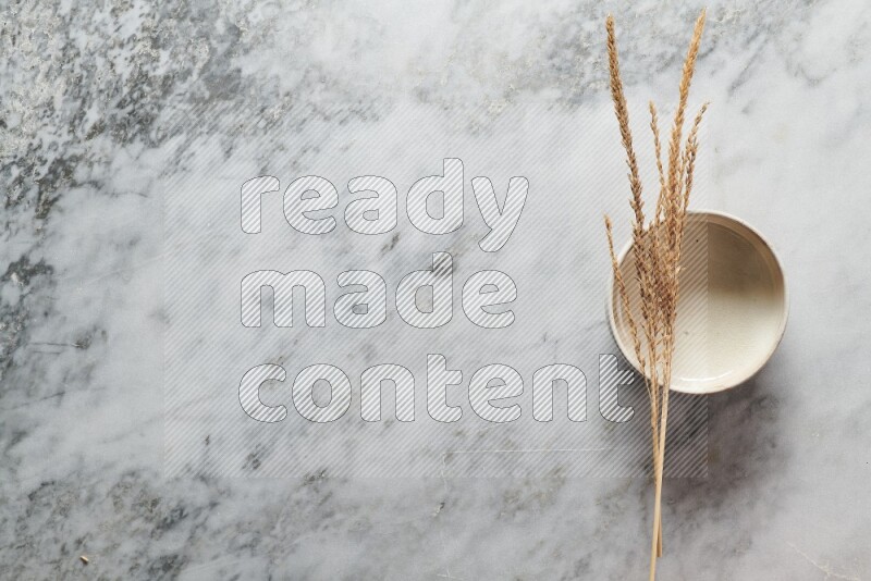 Wheat stalks on beige pottery bowl on grey marble background