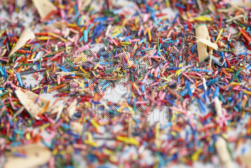 This image showcases a vibrant multicolored pencil shavings scattered on grey background