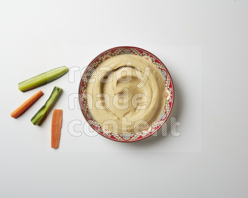Plain Hummus in a red plate with patterns on a white background