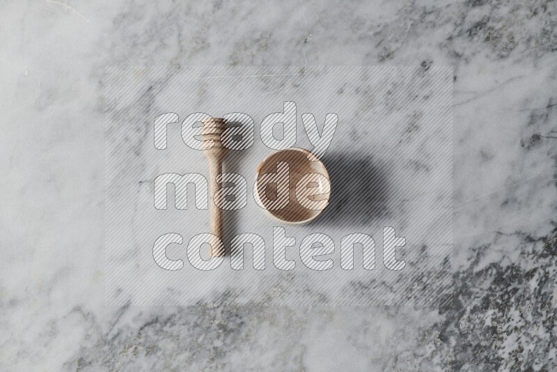 Beige pottery bowl with wooden honey dipper on the side on grey marble background