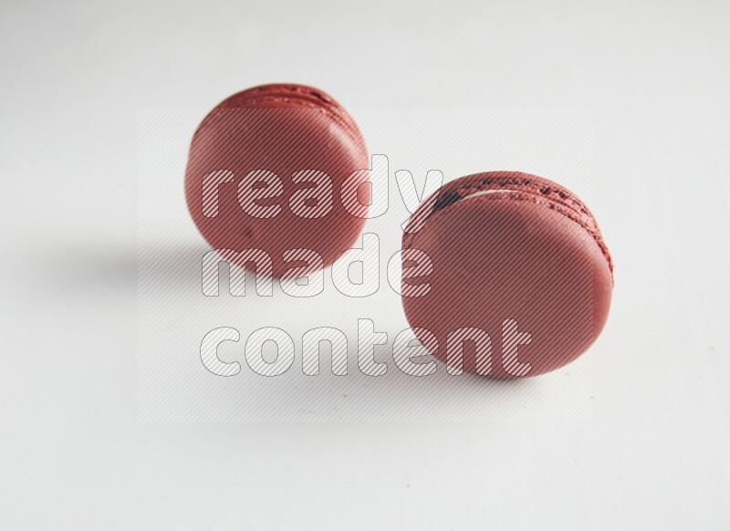 45º Shot of two Red Velvet macarons on white background