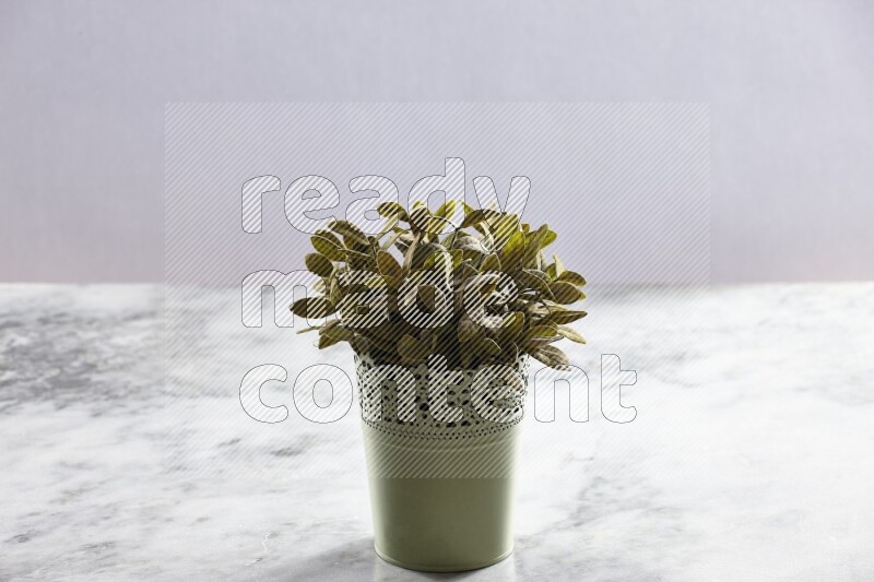 Artificial plant in green decorative pot on grey marble background