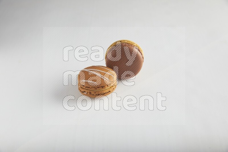 45º Shot of of two assorted Brown Irish Cream, and Yellow, and Brown Chai Latte macarons on white background