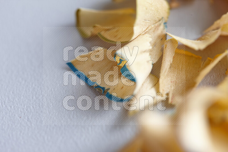 صورة مقربة تظهر كومة صغيرة من نشارة الأقلام ذات حواف ملونة متنوعة علي خلفية رمادية