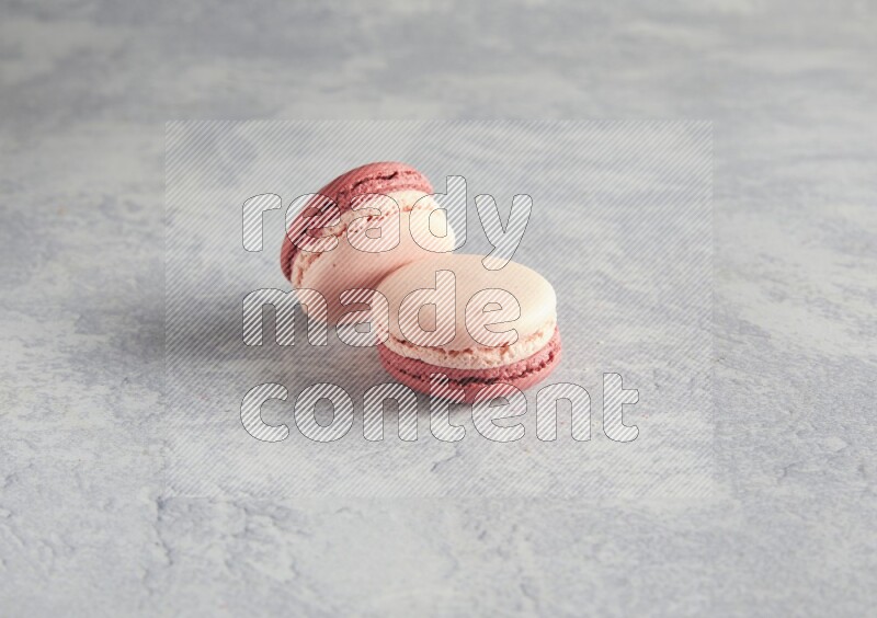 45º Shot of two Pink Litchi Raspberry macarons  on white  marble background