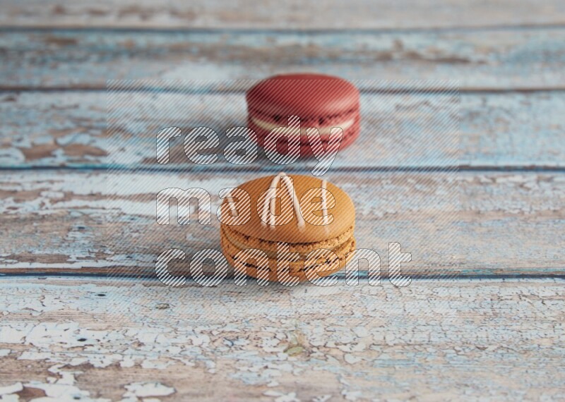 45º Shot of of two assorted Brown Irish Cream, and Red Velvet macarons on light blue background