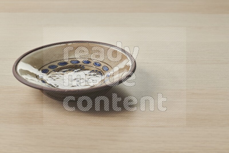 A decorative pottery plate on light wooden background