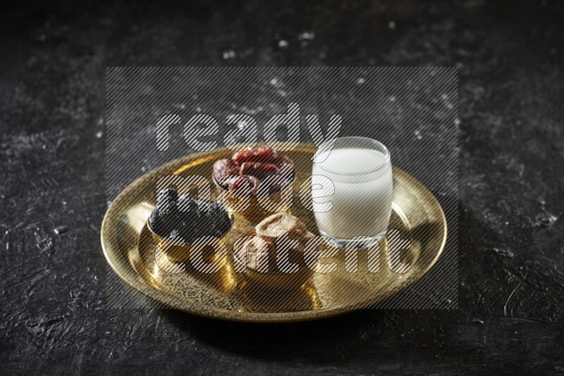 Dried fruits in metal bowls with sobya on a tray in dark setup