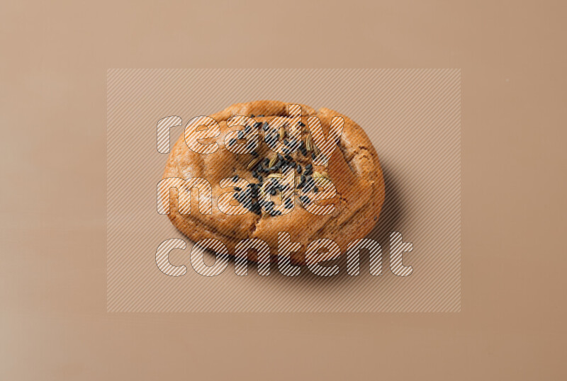 a whole Hasawi cookie with grains on a brown background